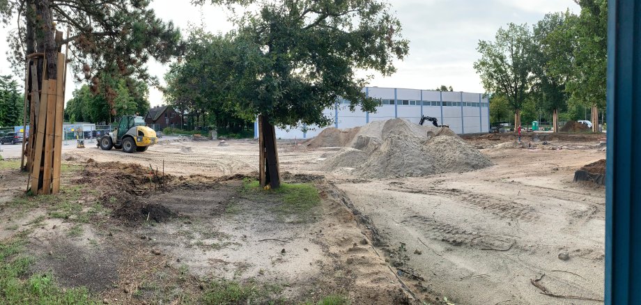 An excavator stands in front of the school building.