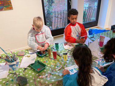 Visita a la galería 2 Niños con batas de pintor pintan con pintura acrílica y pinceles