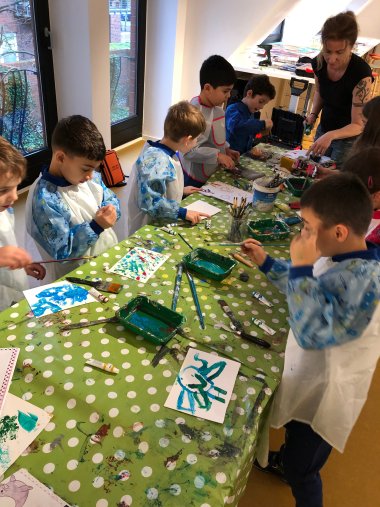 Visita a la galería 8 Niños con batas de pintor pintan con pintura acrílica