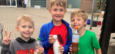Trois garçons montrent leur jus de pomme pressé