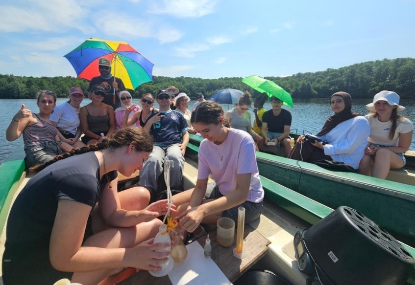 Tijdens een excursie zitten twee jongeren in een klein bootje op een meer en maken ze meetapparatuur klaar voor het wateronderzoek.
