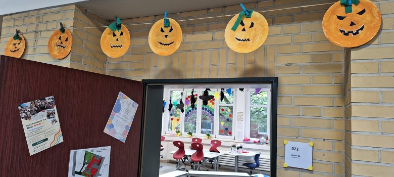 Dia das Bruxas Rostos de Halloween criados numa linha no corredor da escola; o observador pode olhar para dentro da sala de aula