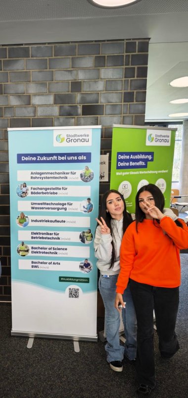 Zwei Schülerinnen stehen neben Informationsaufstellern der Stadtwerke Gronau und zeigen das vielfältige Ausbildungs- und Studienangebot des Unternehmens.